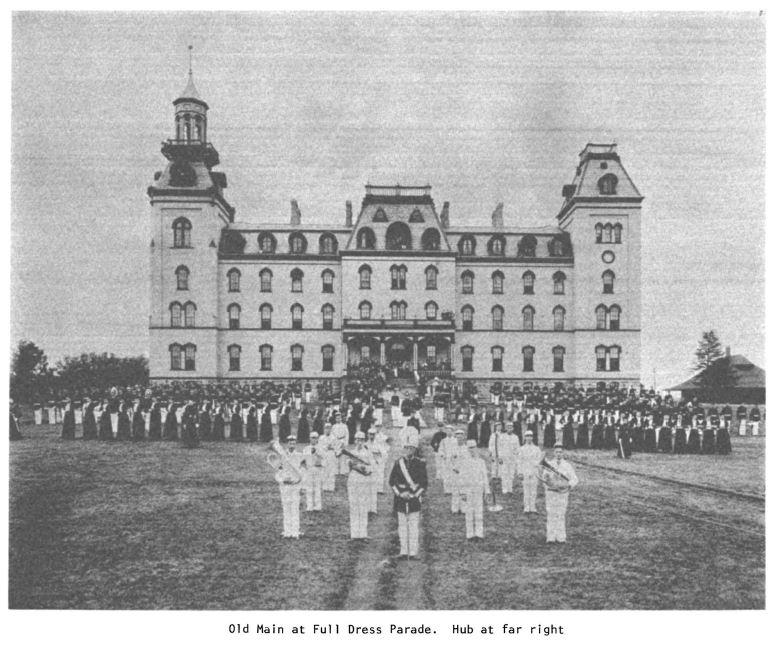 Black and white photograph of Old Main at Full Dress Parade with group of people in military formation in front. Hub at far right